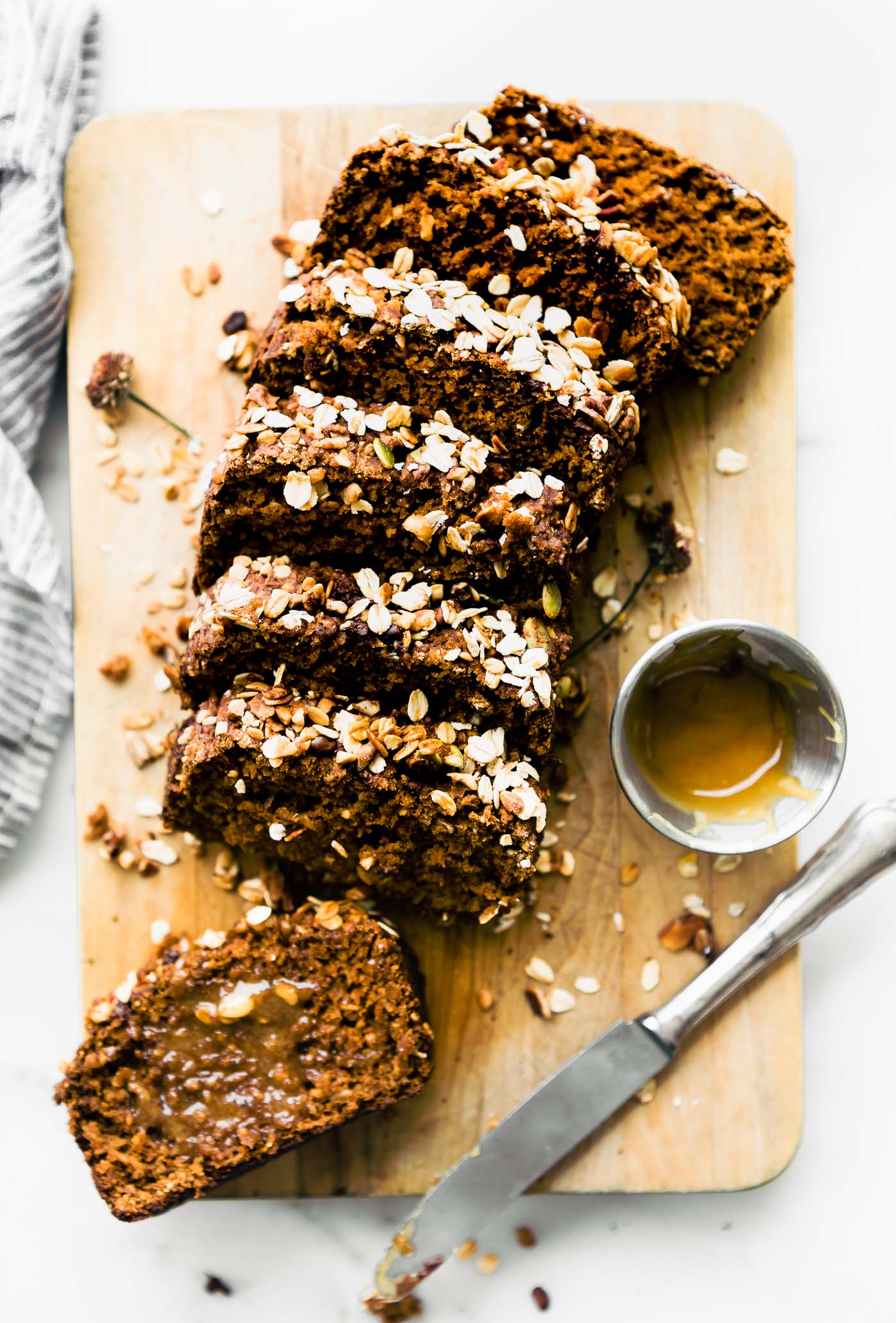 slices of healthy pumpkin bread topped with rolled oats on wooden cutting board