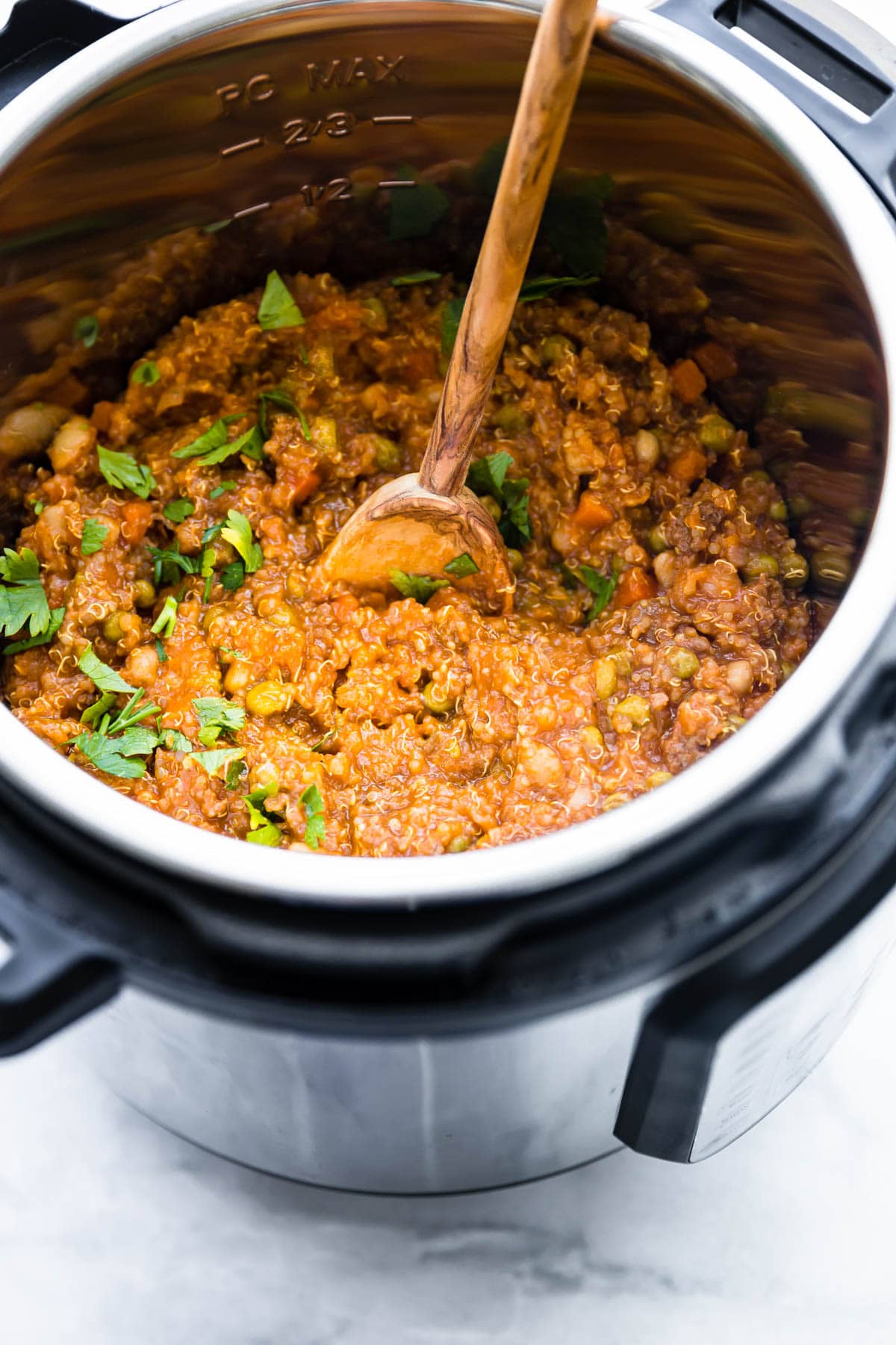 Sausage and quinoa stew in Instant Pot with wooden spoon in stew