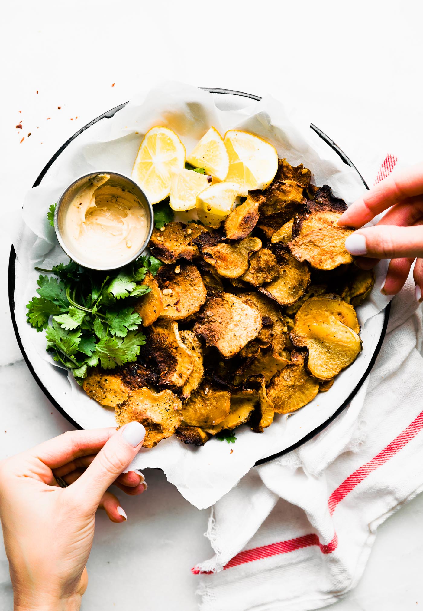A hand removing a baked rutabaga chip round tray piled high with chips.