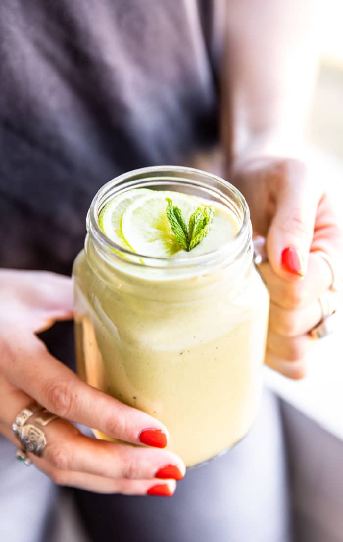 girl holding keto green smoothie in mason jar glass
