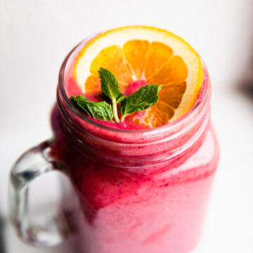 Immunity Boosting Frozen Fruit Smoothie in glass cup topped with fresh orange slice and fresh mint.