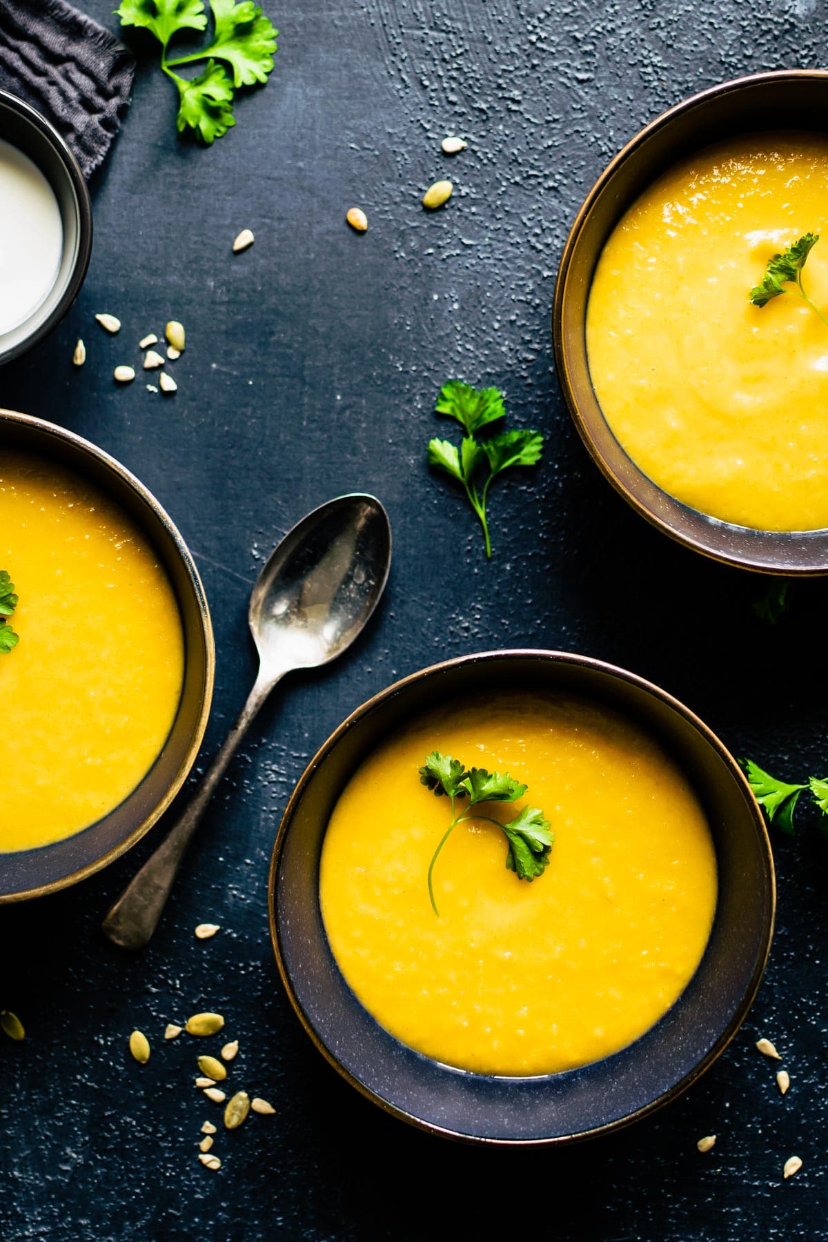 3 bowls of roasted butternut squash soup in black bowls with spoon