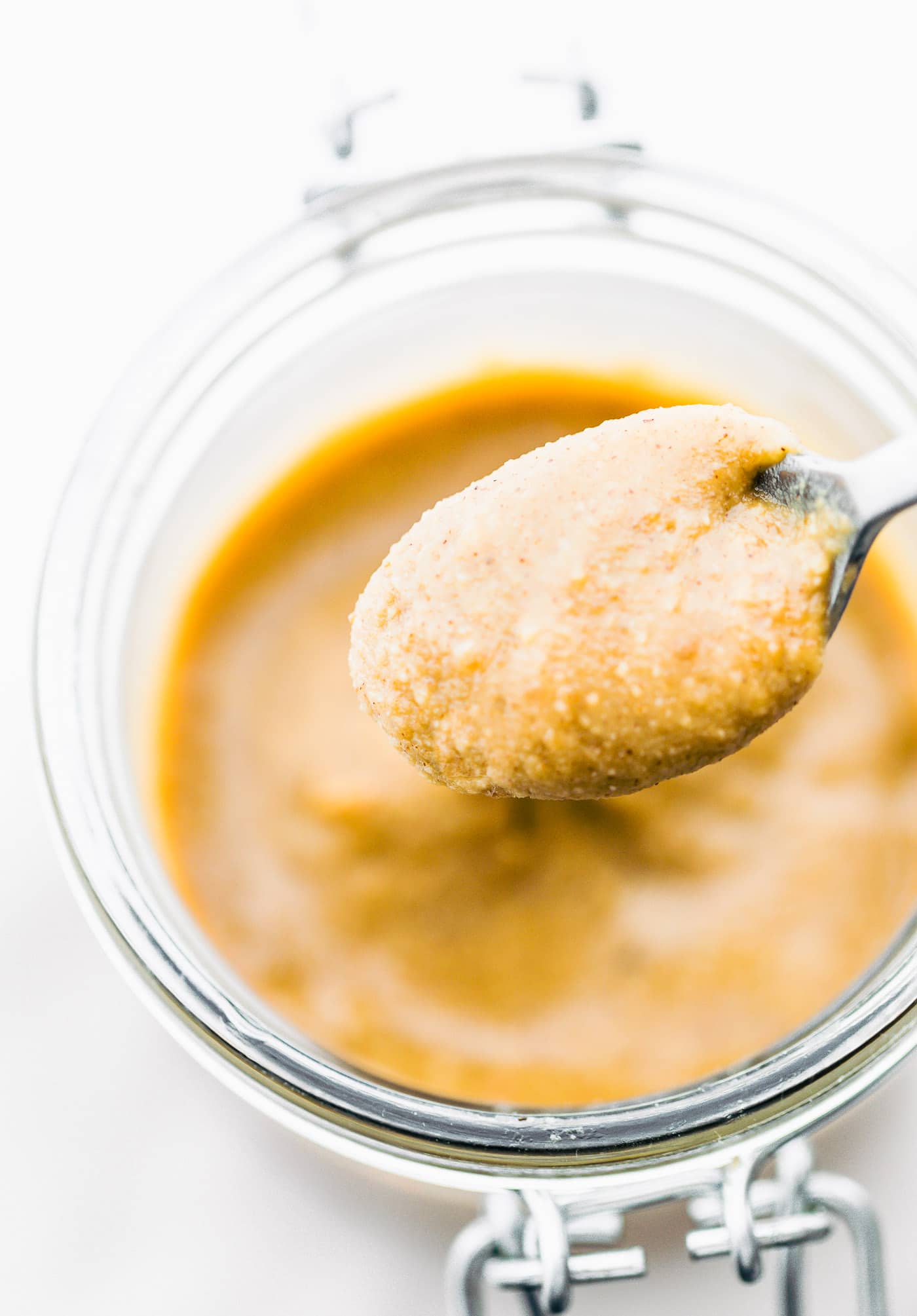 A spoonful of homemade cashew butter dipped into a jar of nut butter.