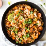 Shrimp jambalaya with lentils and sausage in a white skillet