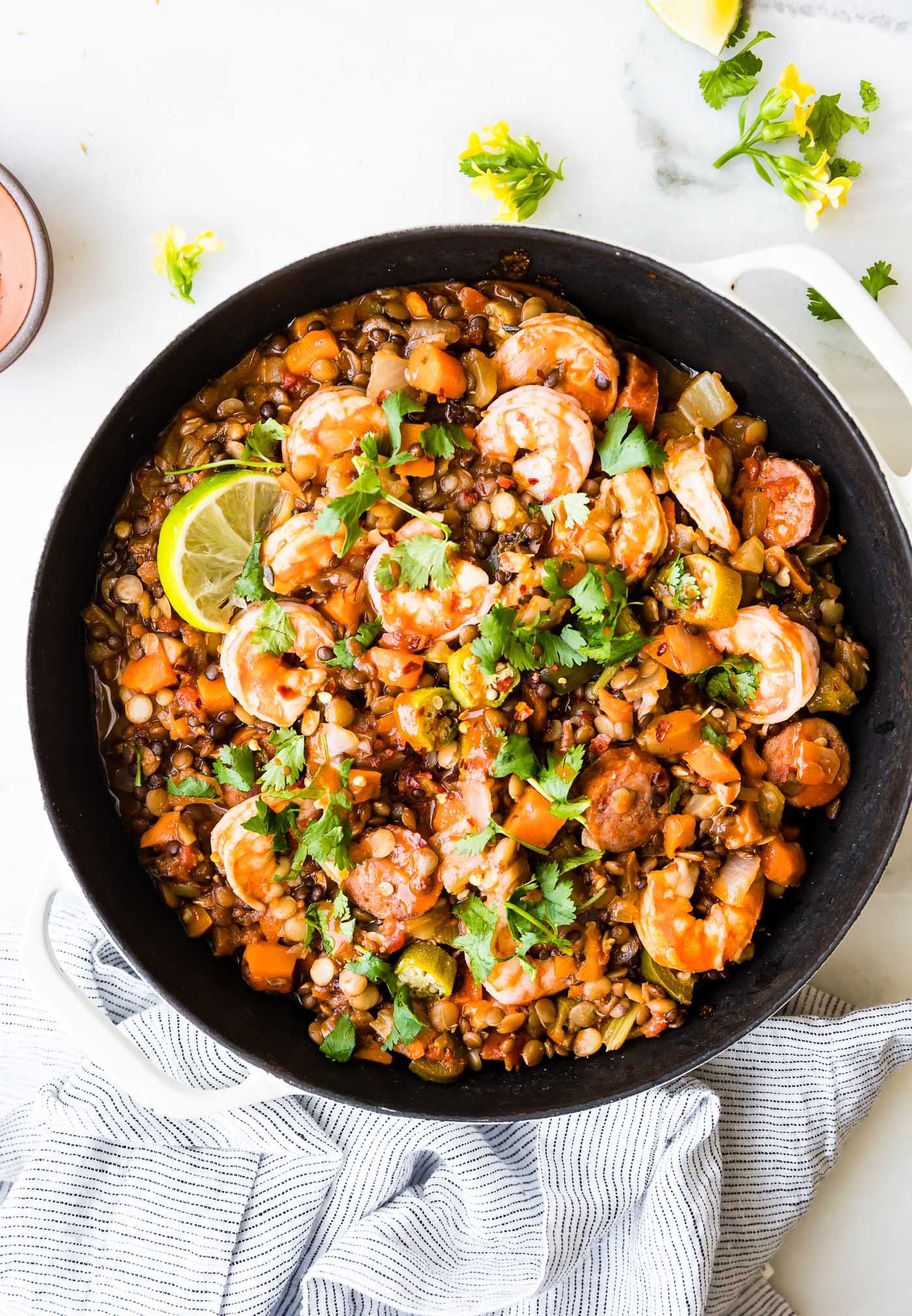 Overhead view shrimp jambalaya with lentils and sausage in a large skillet.