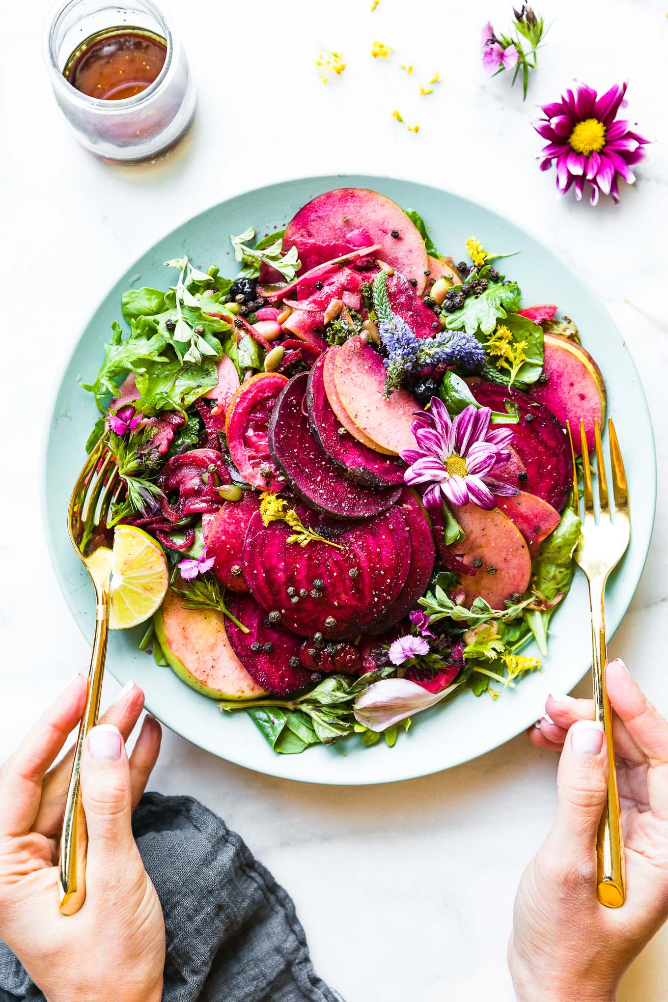 Marinated beet and apple salad over mixed greens on turquoise plate.