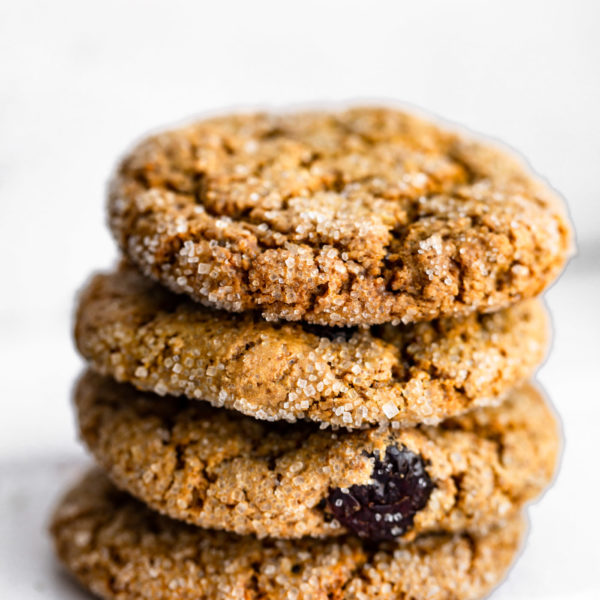 4 vegan cranberry almond molasses cookies stacked on top of each other