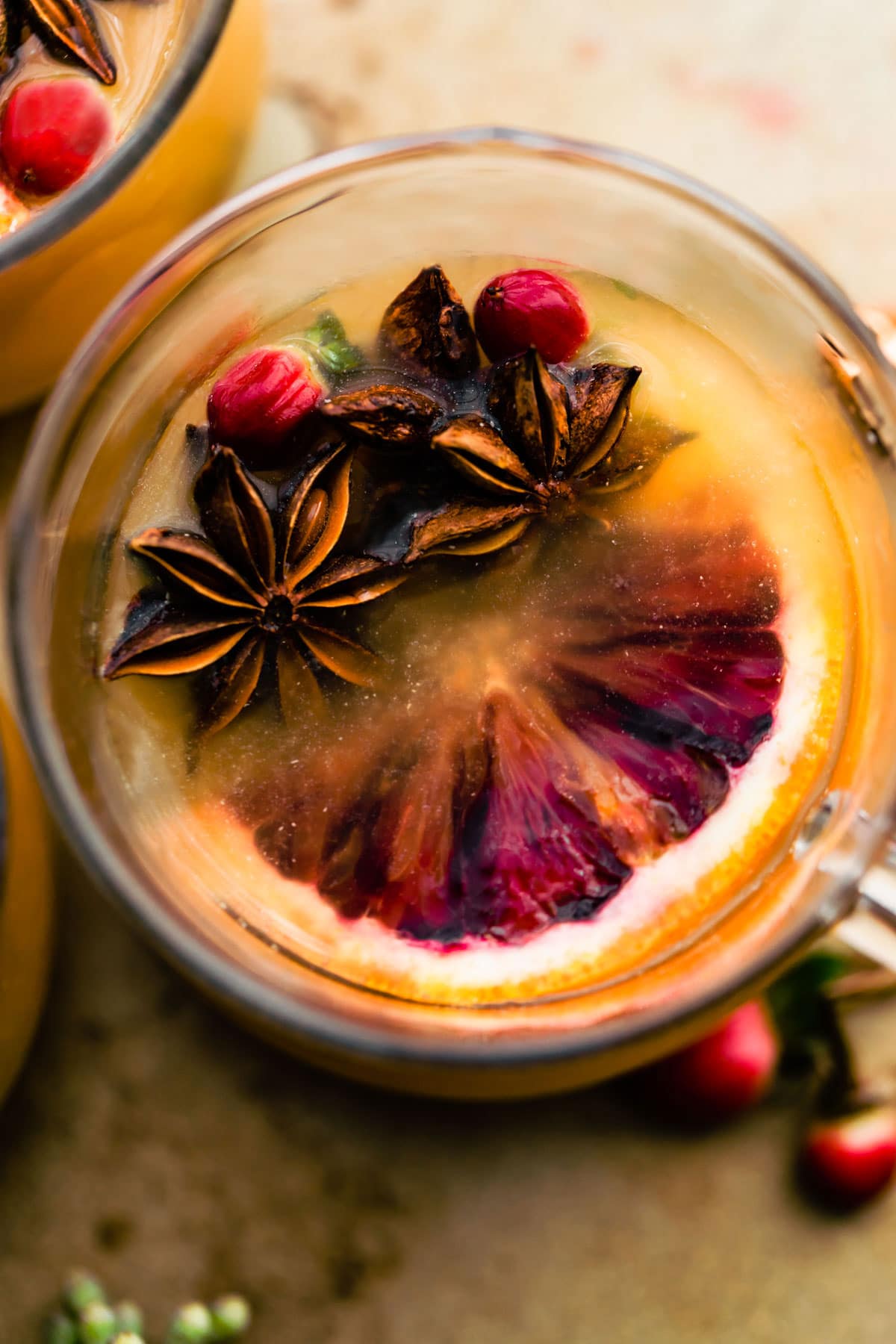 Close up overhead view glass of hot toddy with fresh fruit and spices floating in drink.