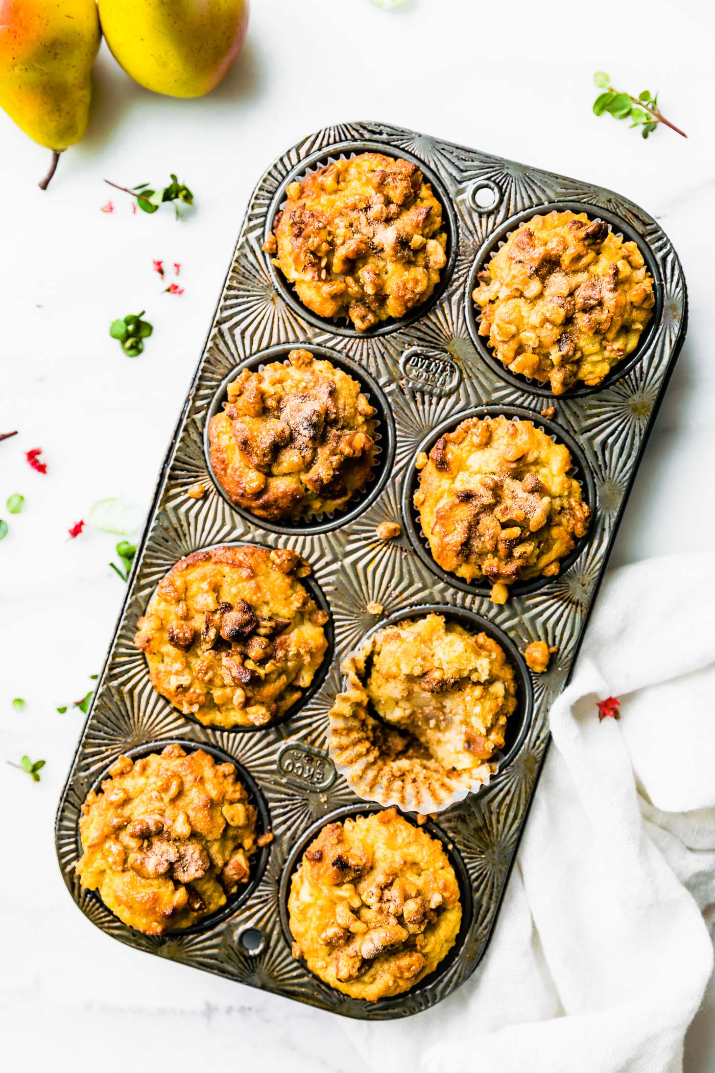 Overhead view spiced pear muffins with nut topping in a muffin tin.