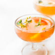 Two cocktail glasses filled with citrus paloma cocktail, orange slices floating in drinks