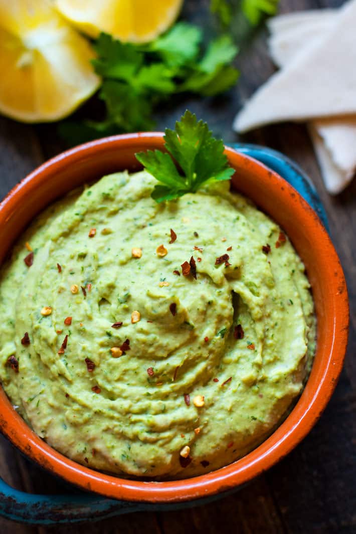 Easy Chimichurri White Bean Hummus in an orange bowl topped with red pepper flakes.