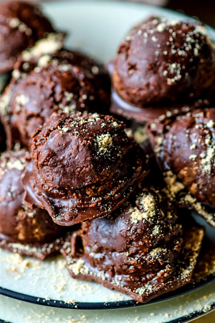 chocolate peanut butter cookie dough bites with hidden veggies stacked in a small pile sprinkled with peanut flour.