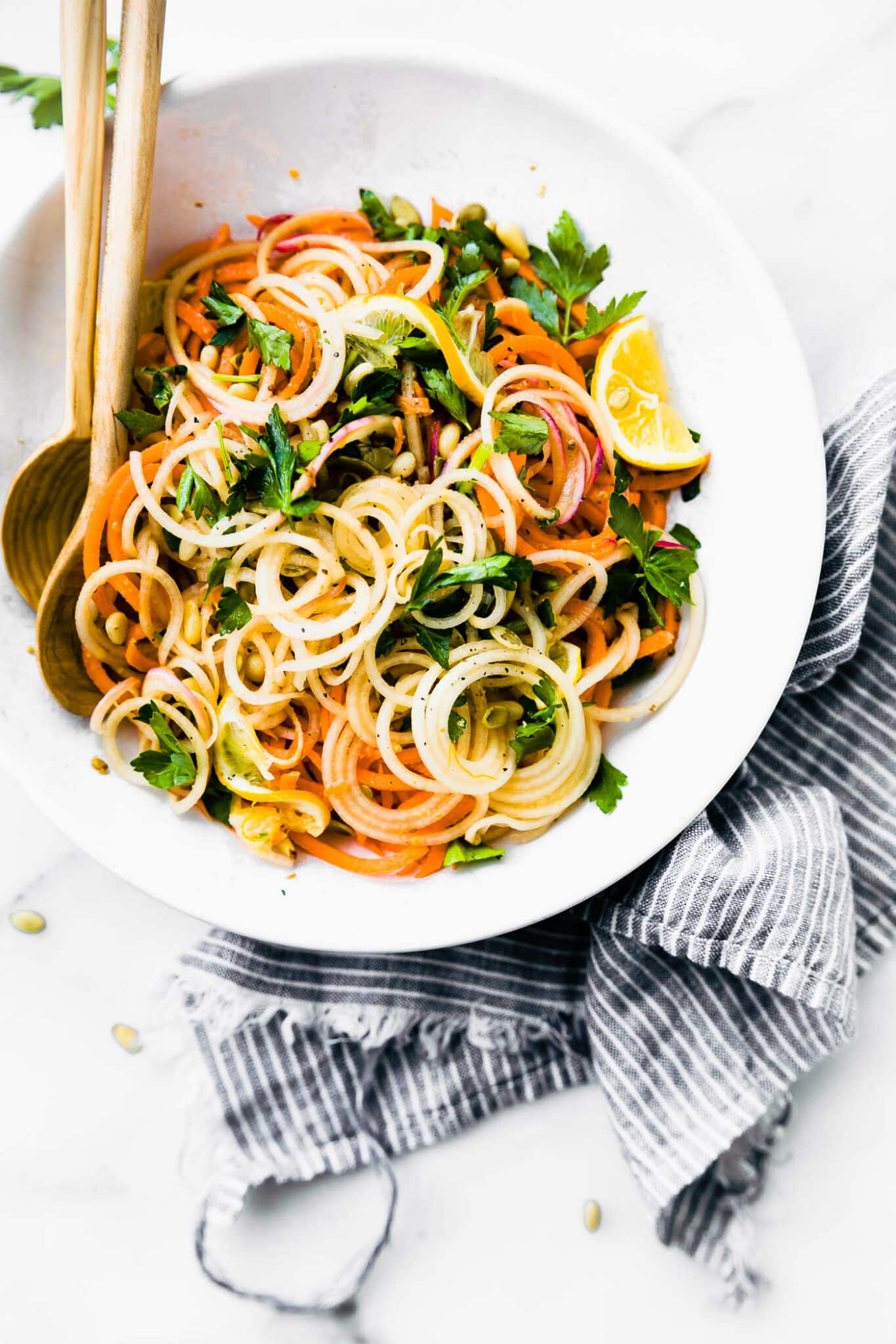 Overhead view carrot and celery root spiralized 'noodles' salad in white bowl.