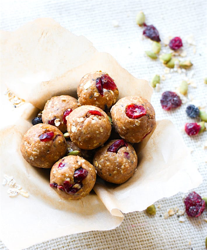 No Bake Cranberry Muesli Energy Bites made with almond butter rolled to bite-size balls in a parchment-covered bowl