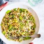 A toasted pine nut quinoa salad with leeks in white serving bowl.