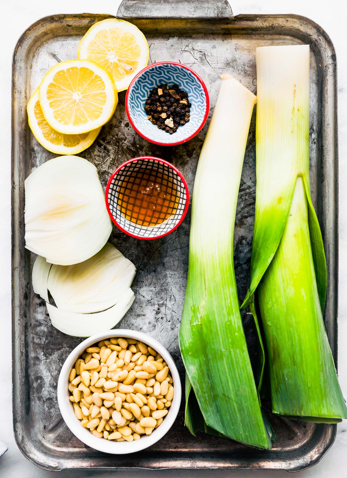 All ingredients for quinoa salad with leeks and pine nuts in a silver tray.