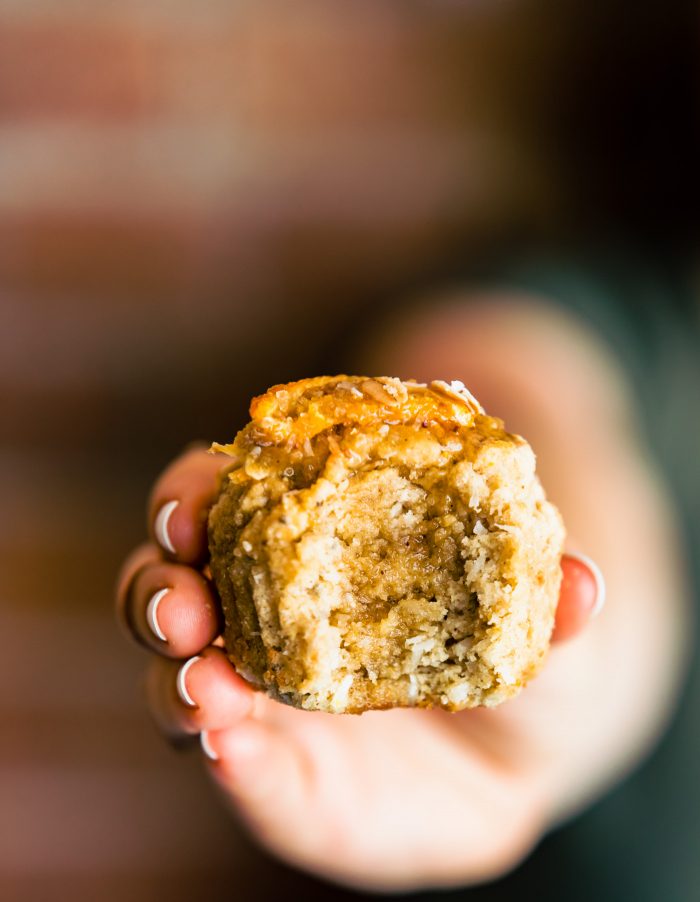 woman's hand with gluten free muffin with bite taken out, holding towards the camera