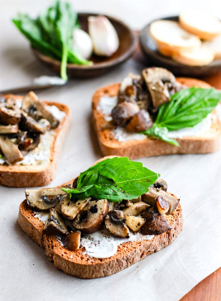 Simple creamy garlic herb mushroom toast recipe! This is one savory vegetarian gluten free appetizer that's packed full of flavor! Buttery sautéed garlic mushroom toast with cream cheese, cracked pepper, and basil made into one super easy and delicious gluten free snack or appetizer. It's a staple gluten free recipe I keep handy for parties, holidays, or even for a quick light meal.