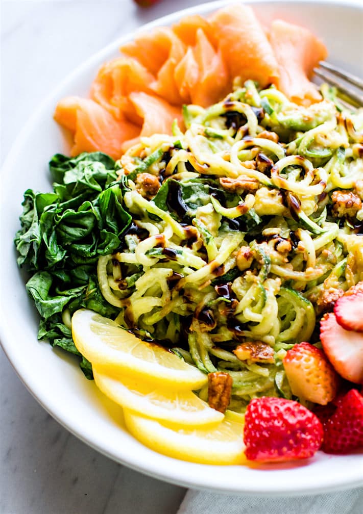 Smoked Salmon and Strawberry Zucchini Noodle Pasta Salad! A healthy lower carb Zucchini noodle pasta salad with a creamy avocado sauce and paired with the fresh strawberries, spinach, and smoked salmon. This gluten free Salad bowl is perfect for a spring or summer lunch or side dish. Clean ingredients, real food, UNREAL GOOD!