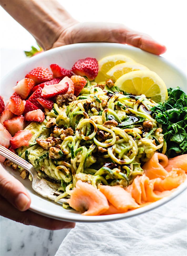 Smoked Salmon and Strawberry Zucchini Noodle Pasta Salad! A healthy lower carb Zucchini noodle pasta salad with a creamy avocado sauce and paired with the fresh strawberries, spinach, and smoked salmon. This gluten free Salad bowl is perfect for a spring or summer lunch or side dish. Clean ingredients, real food, UNREAL GOOD!