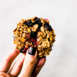 one bowl berry oatmeal breakfast cookie being held against white background.