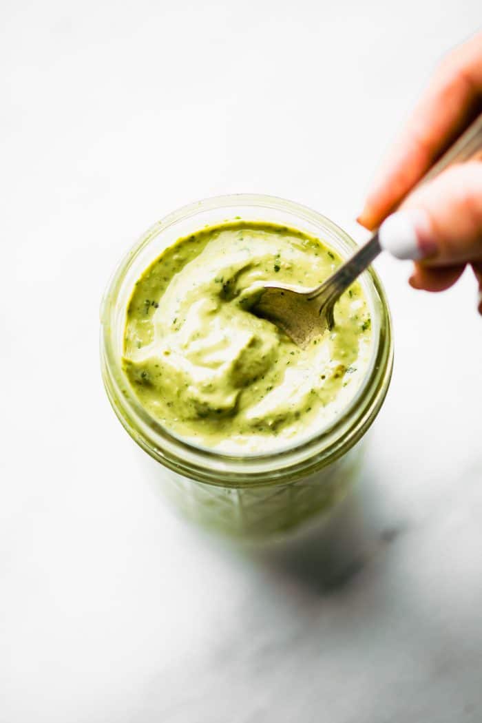 Creamy green avocado dressing in mason jar with spoon