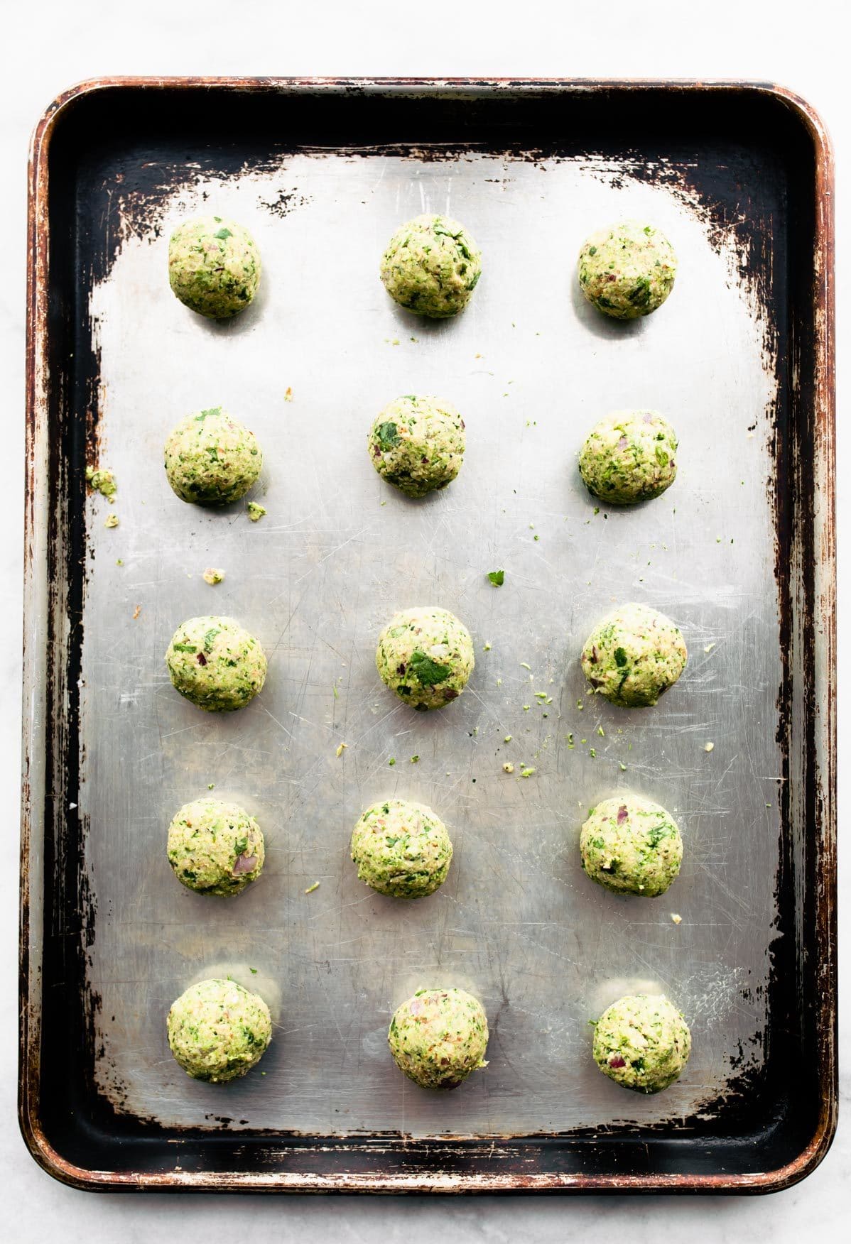 Entire silver baking sheet filled with lined up raw Mexican vegan falafel balls