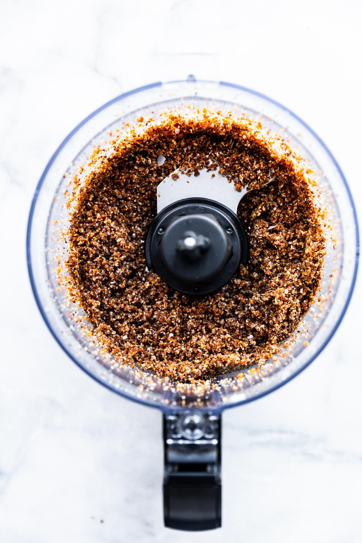 Overhead view food processor bowl filled with crust ingredients for chocolate cashew fig bars.