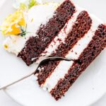 layered chocolate cake with icing , sliced with fork in middle