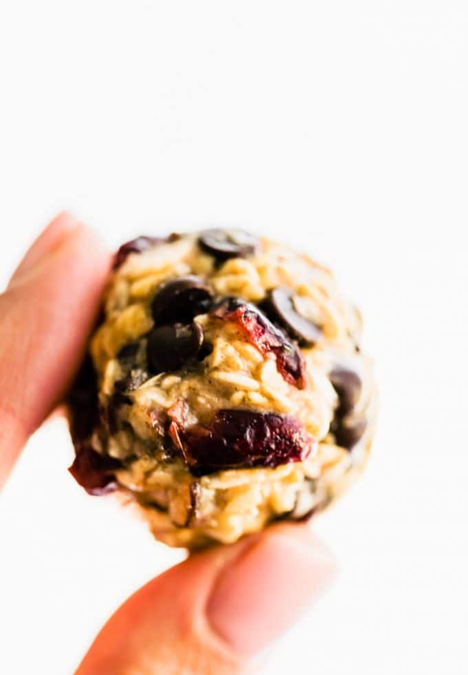 close up of hand holding chocolate chip oatmeal and cranberry oatmeal energy ball.