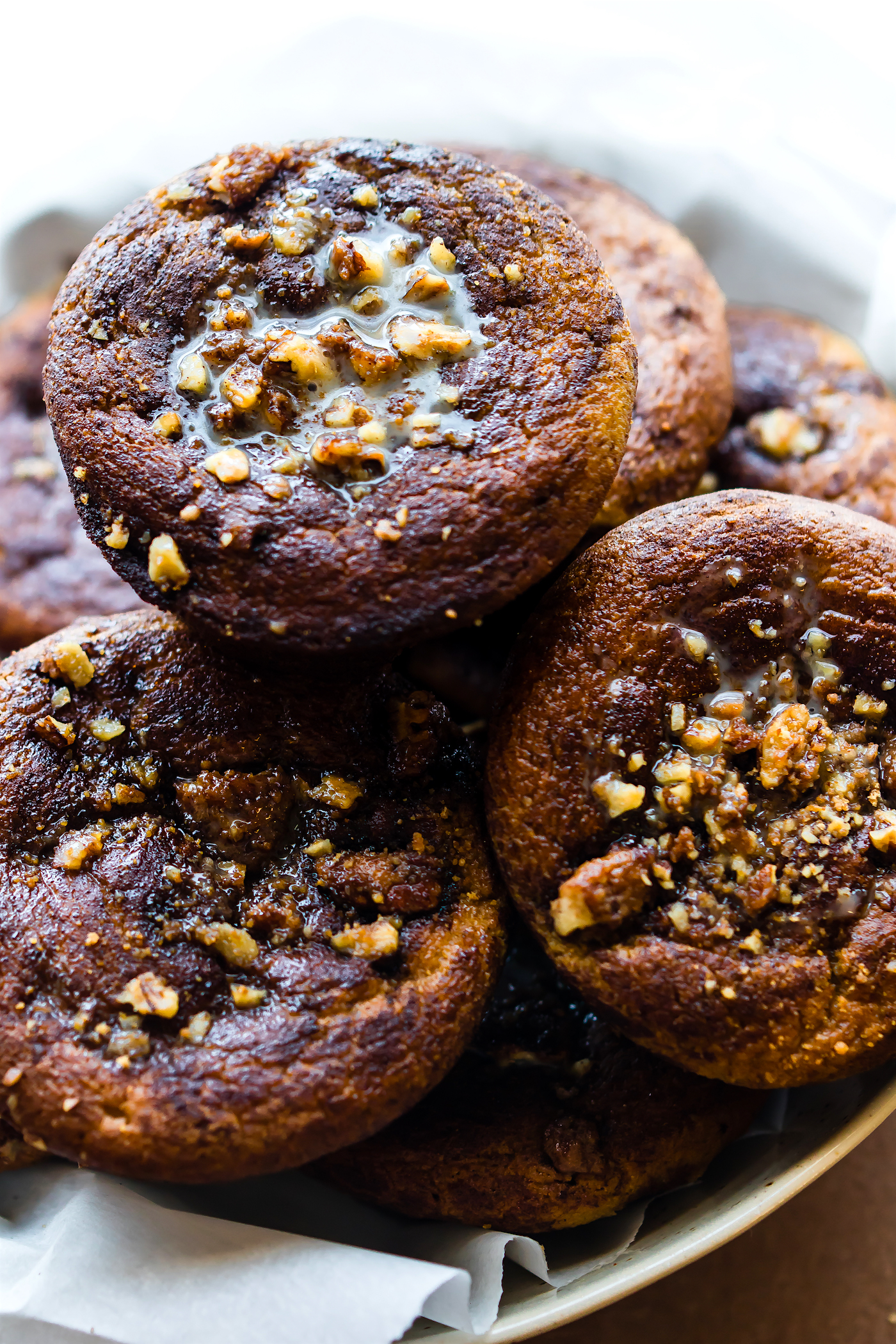Close up view of a pile of gluten-free coffee cake muffins topped with a sticky nut drizzle.