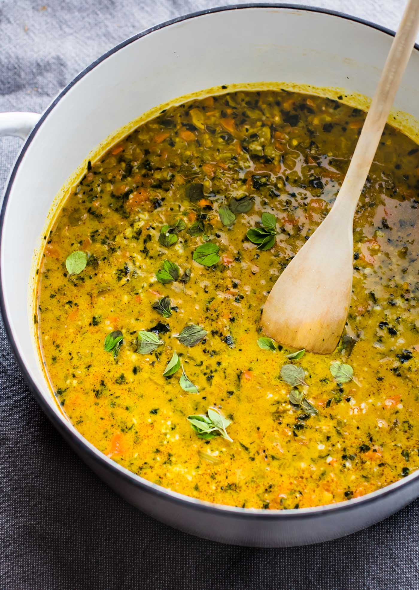 overhead image: wooden spoon in large pot of Curried Cauliflower Rice Vegan Kale Soup