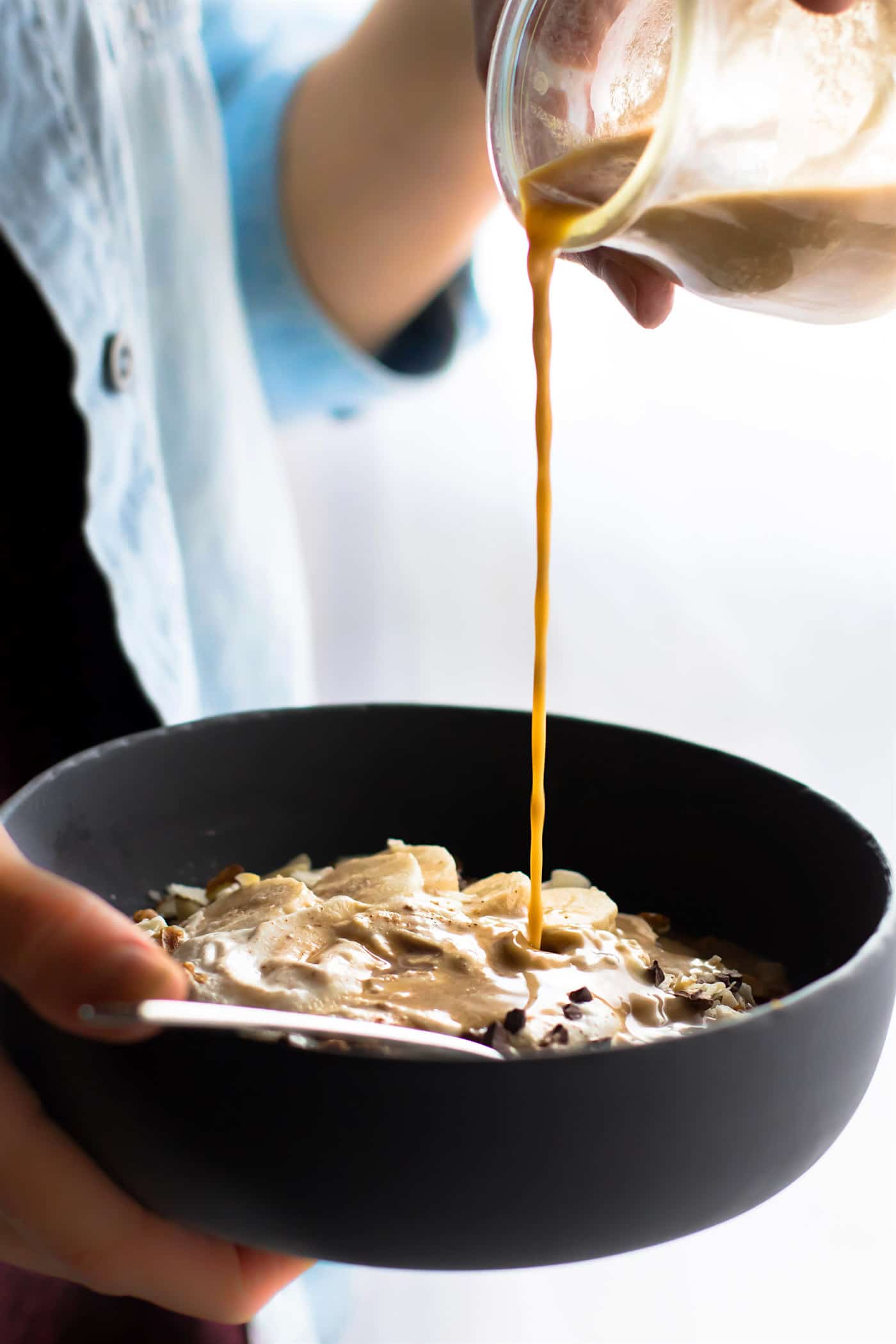pouring coconut milk dirty chai onto a detox breakfast bowl