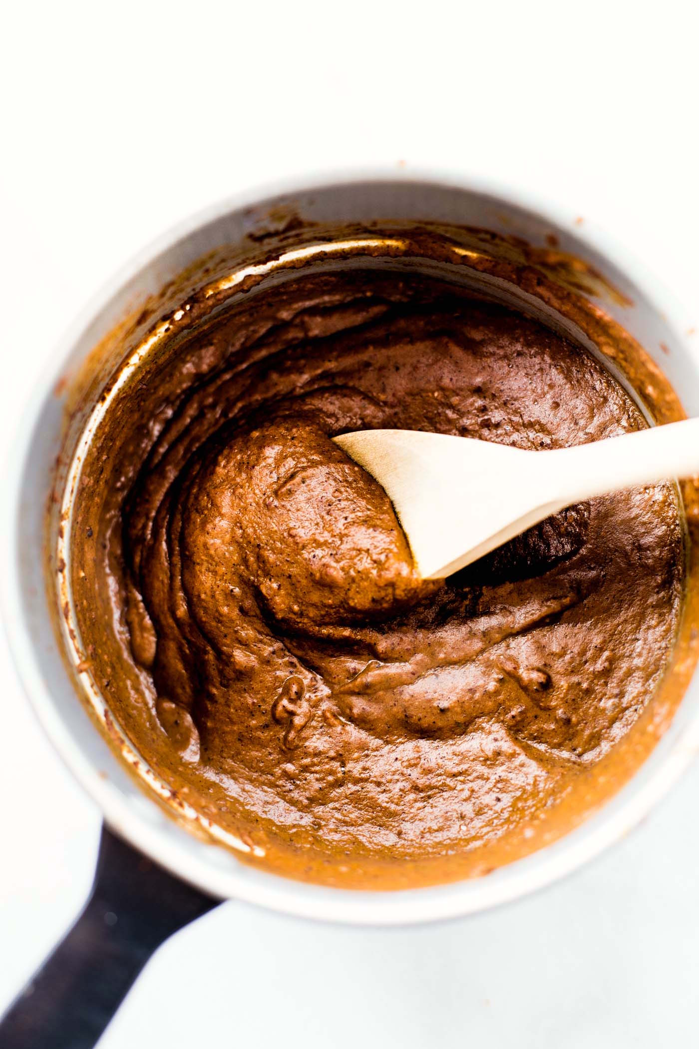 Homemade mole sauce in a small pot with a spoon