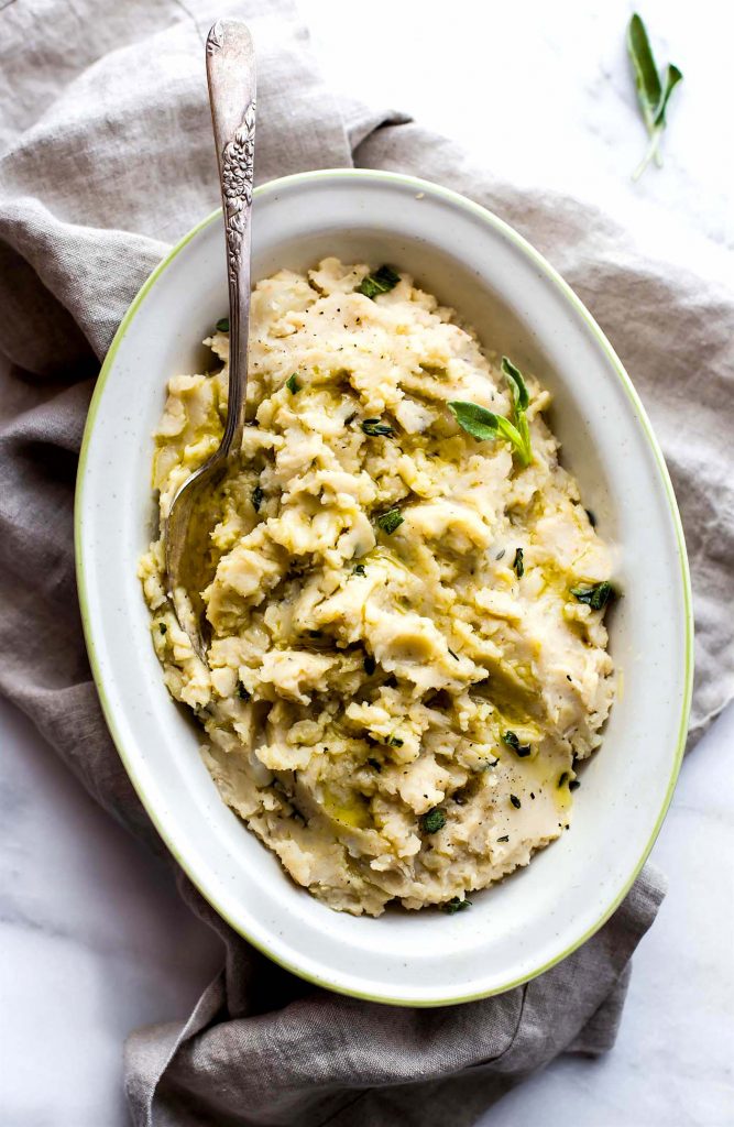 Slow cooker white bean mashed potatoes in serving bowl with silver spoon.