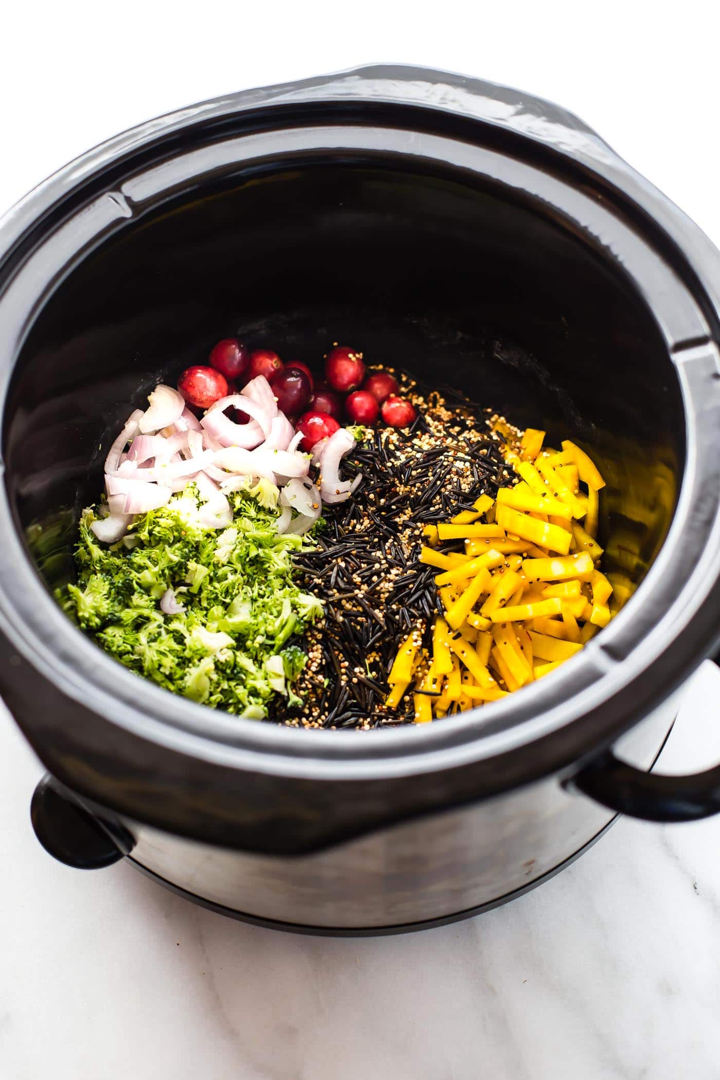 slow cooker filled with uncooked vegetables and wild rice