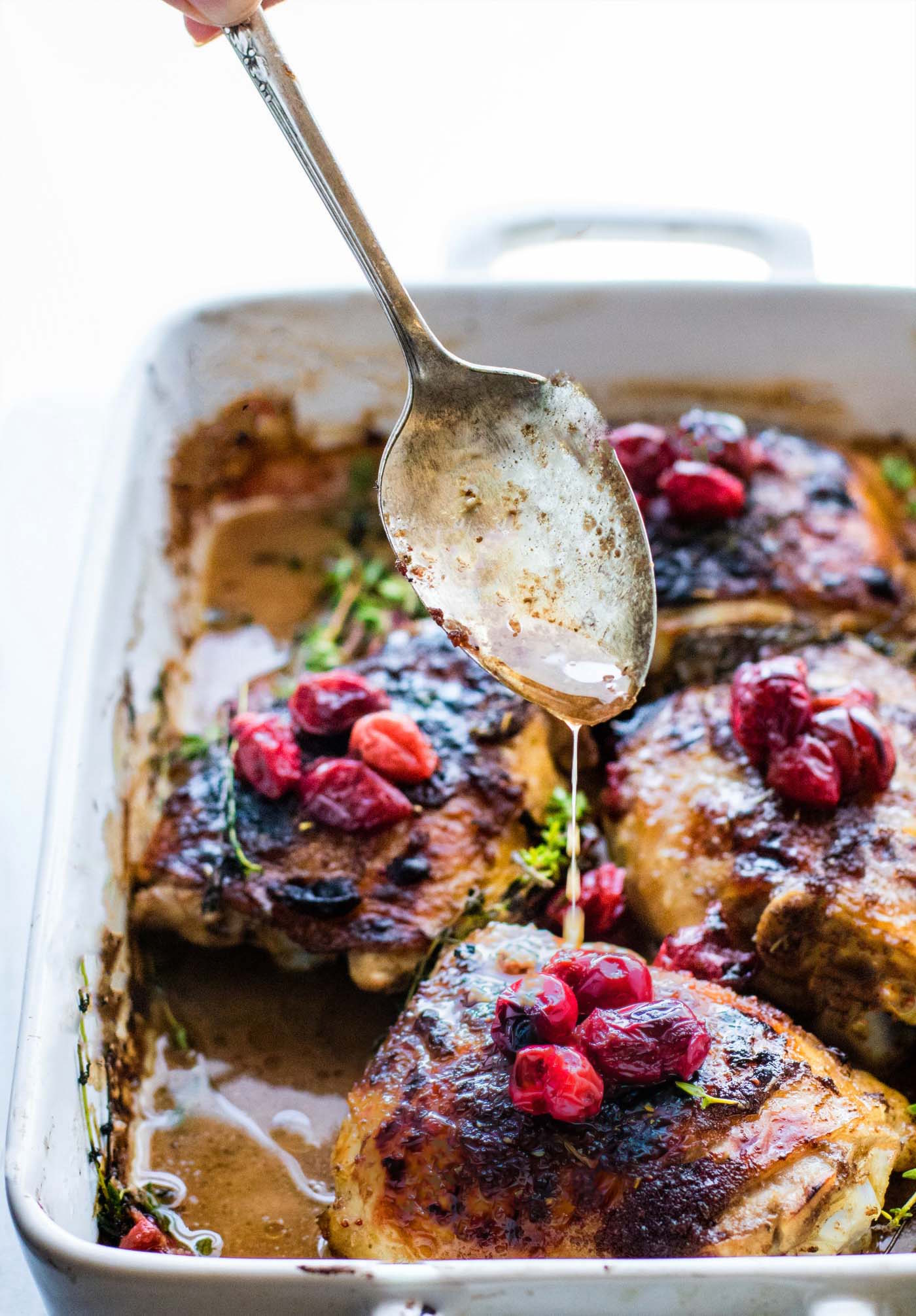 drizzling balsamic marinade over pieces of roasted cranberry chicken
