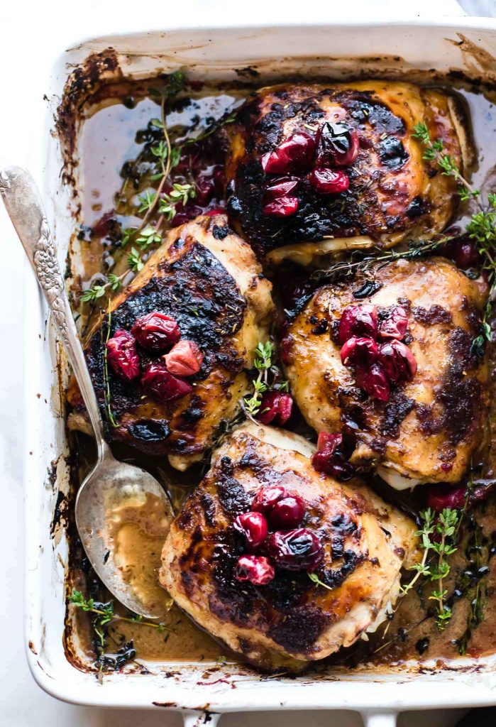 Overhead view balsamic roasted chicken thighs with cranberries in baking dish