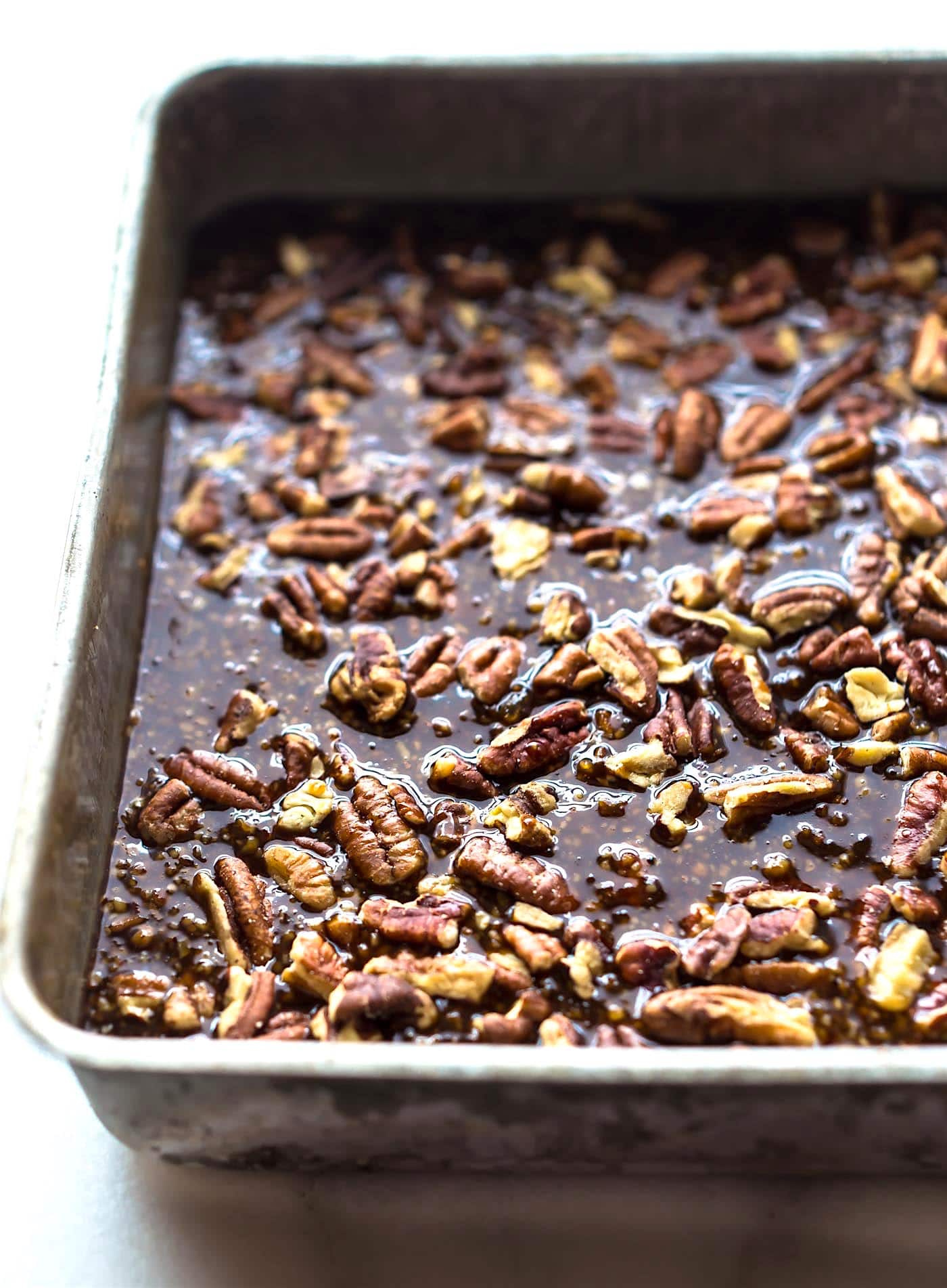 pecan pie filling in square pan with pecans on top