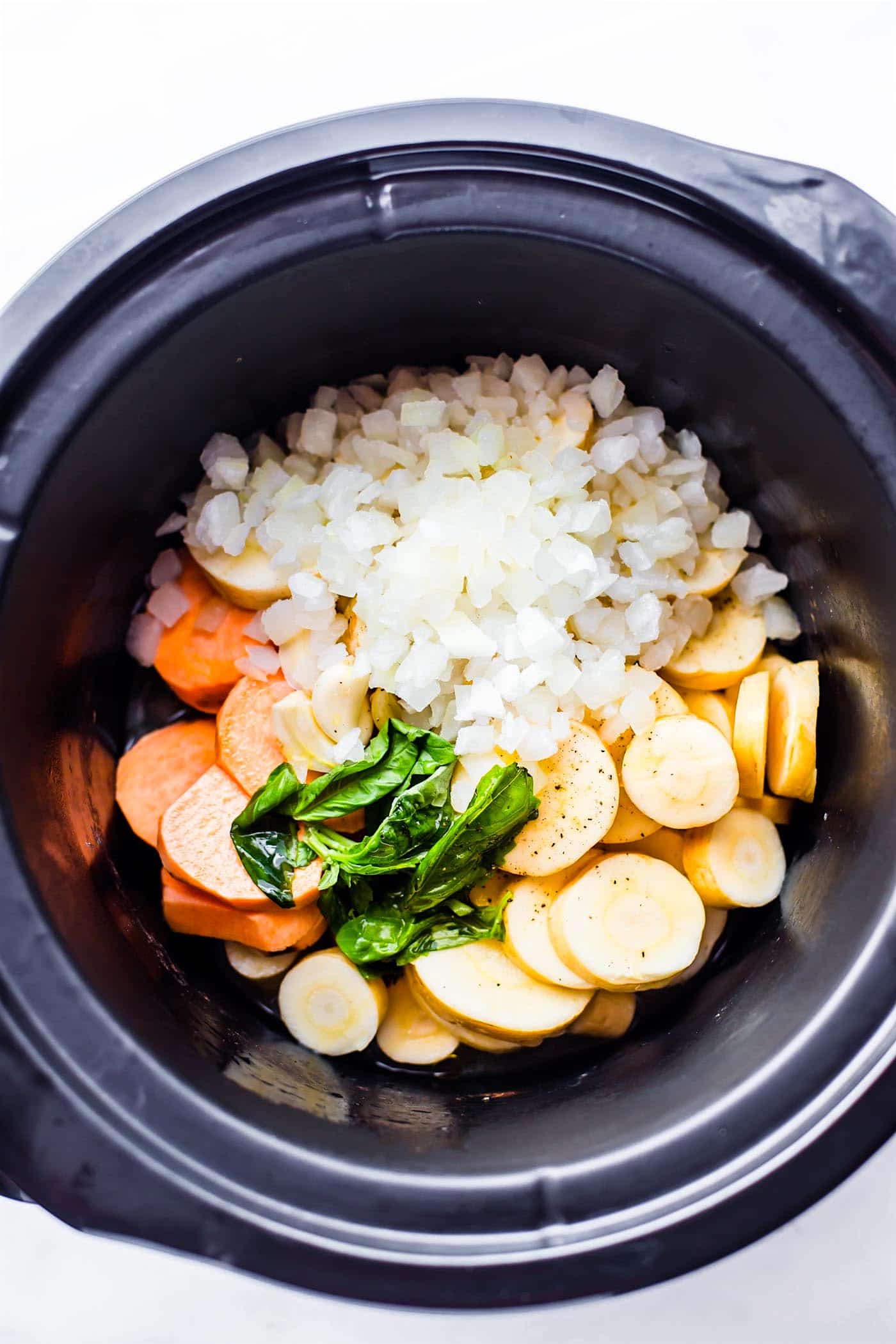 raw onions, potatoes, parsnips, and carrots in a slow cooker