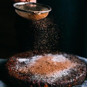 dusting cacao powder over a chocolate Christmas cake