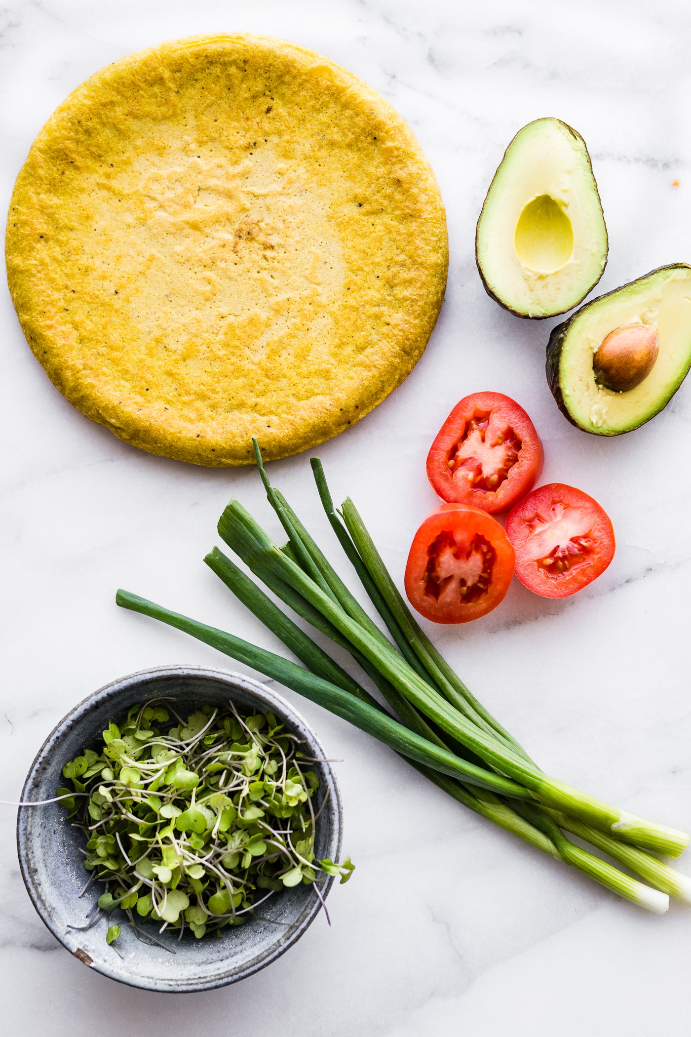 Avocado Tomato Gouda Socca Pizza recipe to love! A grain free, gluten free Avocado Tomato Gouda Socca Pizza made with chickpea flour and topped with Avocado, Gouda, Tomato, and Greens! Seriously easy to make, egg free, vegan option, OMG delicious!