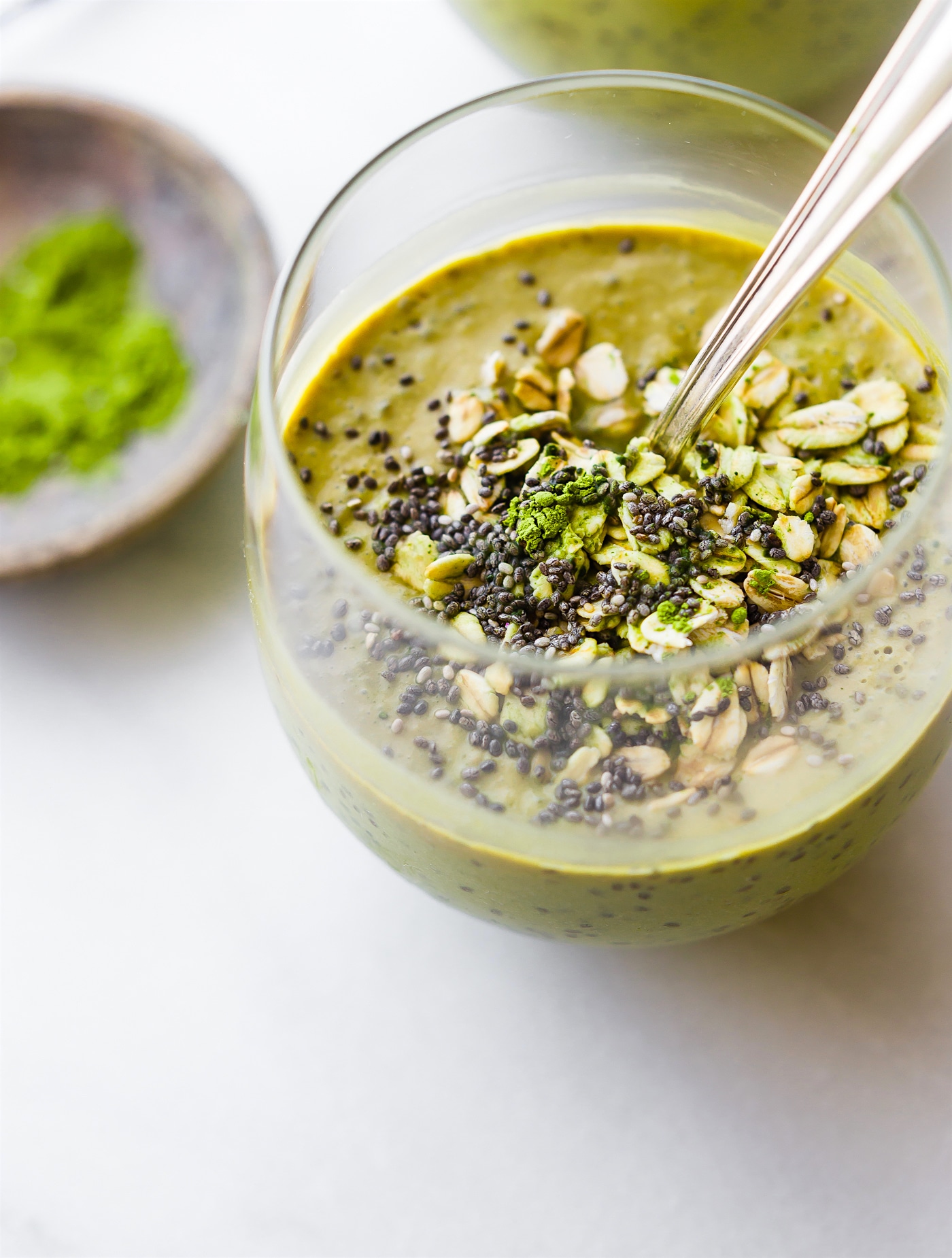 overhead photo: healthy green smoothie topped with nuts and seeds