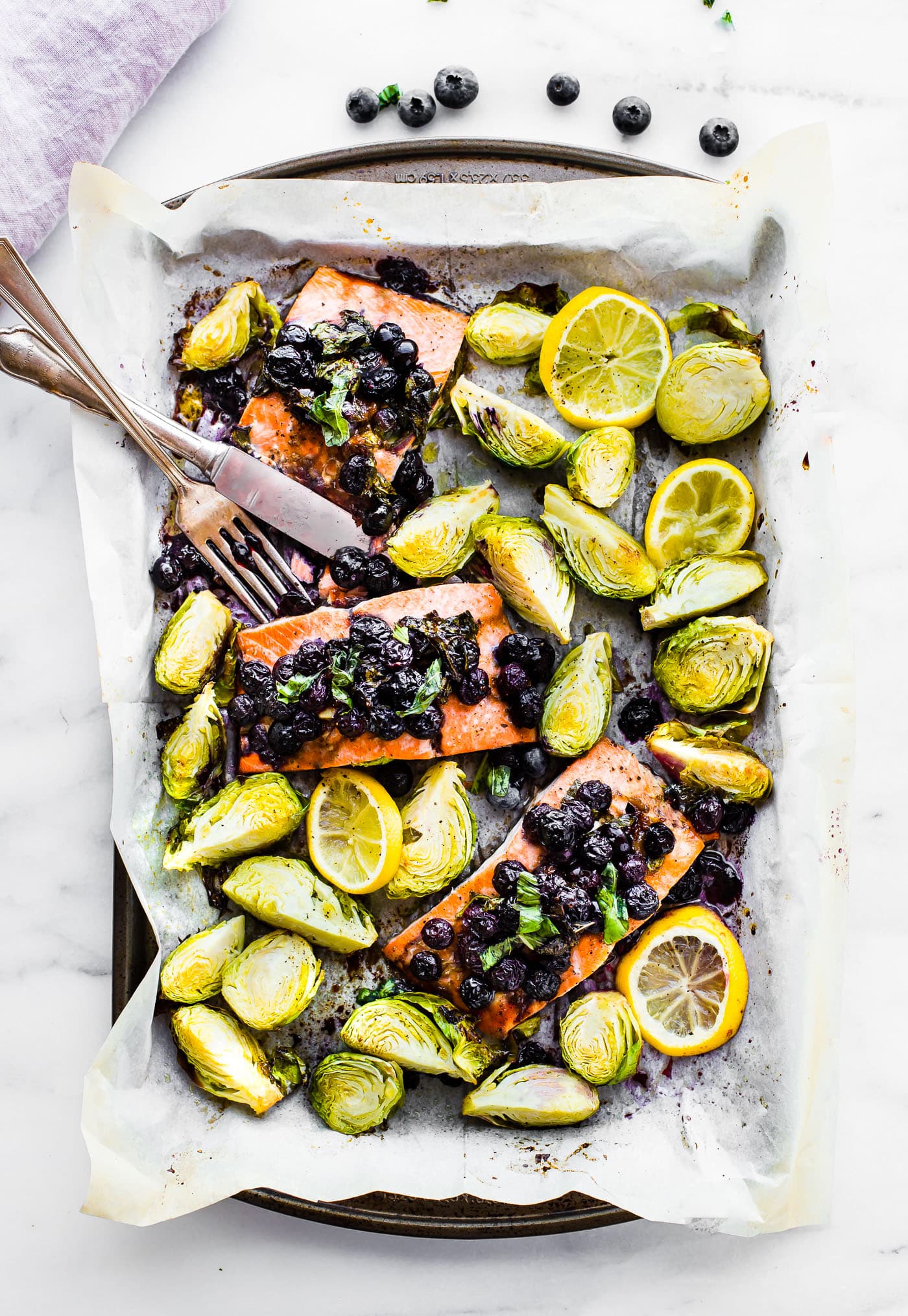 One pan Paleo SUPERFOOD Baked Salmon! This baked salmon recipe is ready in 20 minutes and packed full of nutrients. A nourishing, whole 30 friendly, flavorful meal! Salmon baked with a zippy basil blueberry balsamic topping and crispy Brüssel sprouts! Get your sheet pan ready for dinner! www.cottercrunch.com