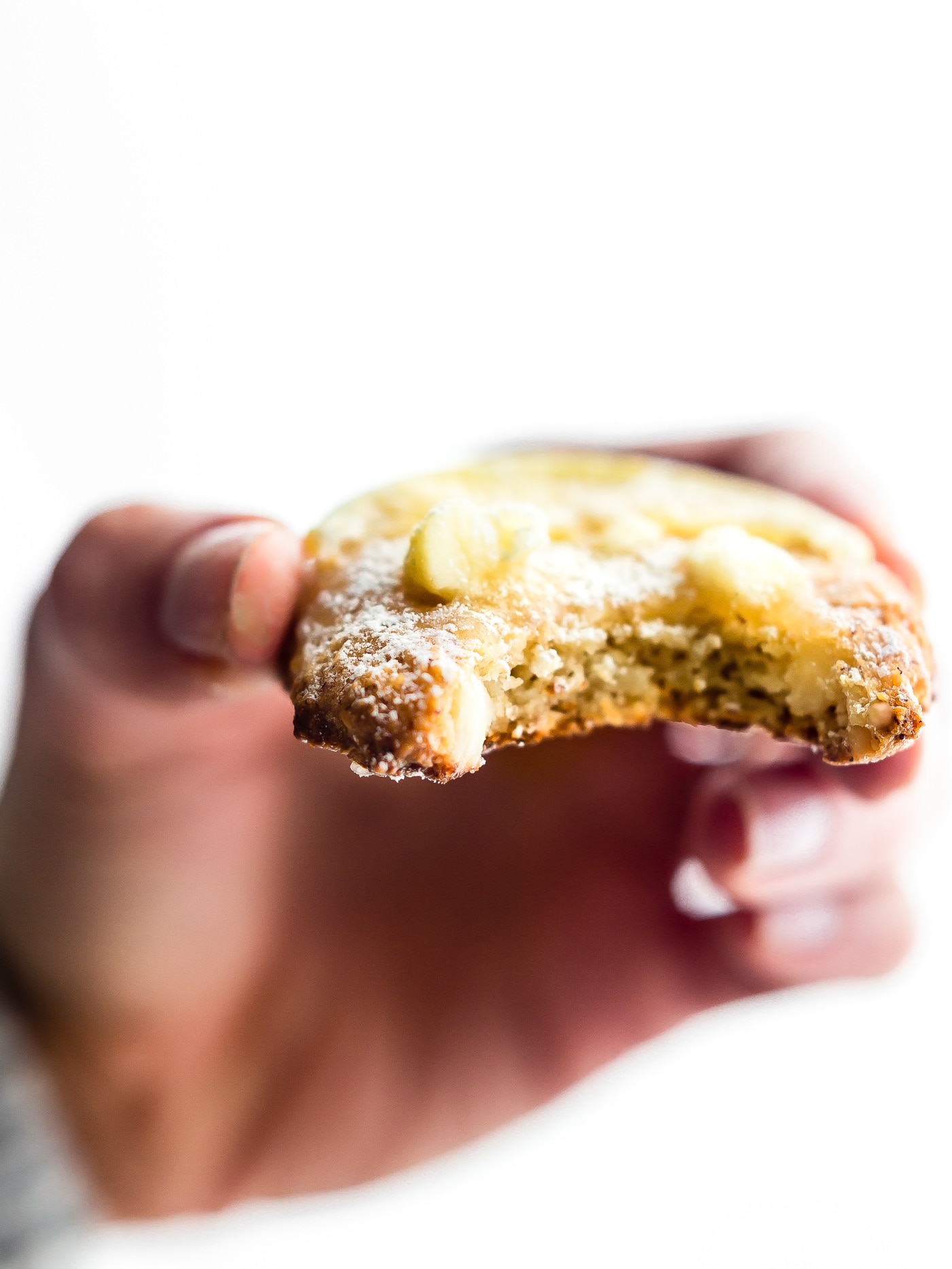 hand holding a lemon glazed cookie with bite taken out of it