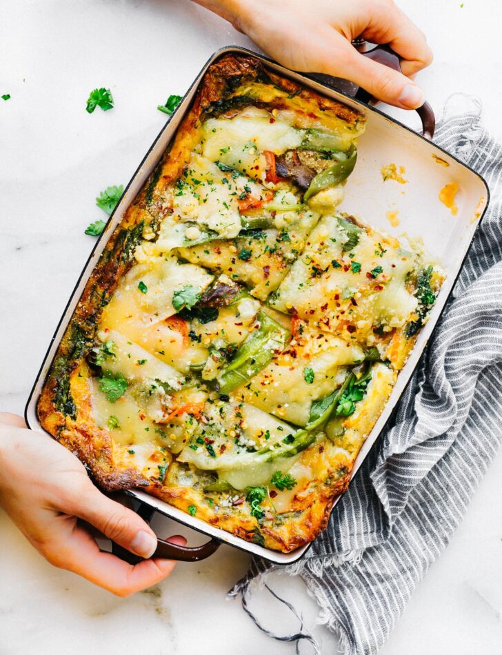 Hatch Green Chile Egg Casserole in baking dish being held by two hands.