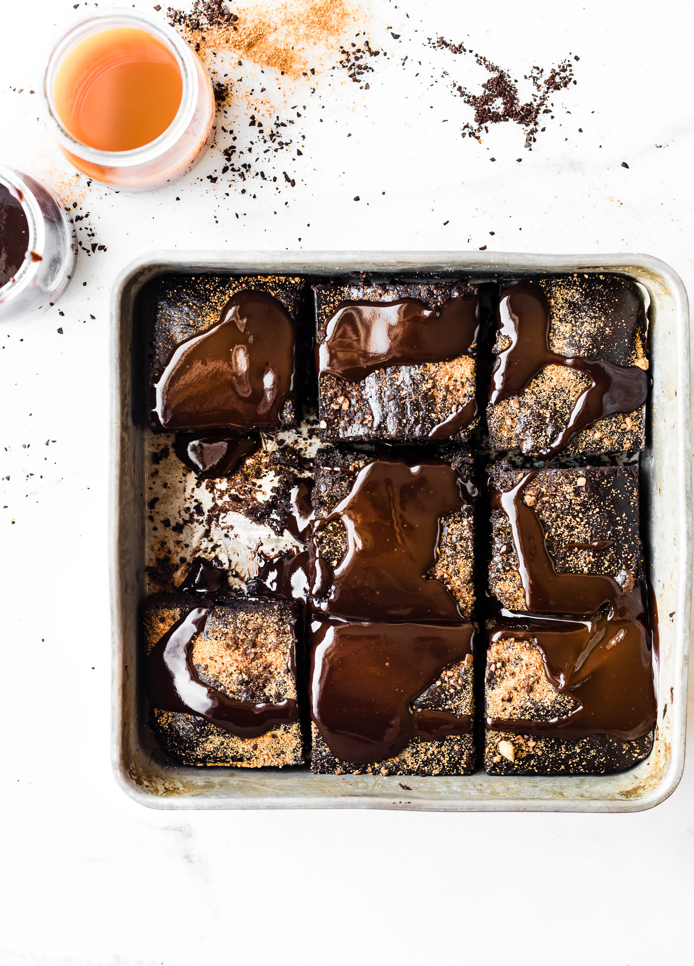 Overhead view dirty chai flourless brownies in pan cut into squares with glossy dark chocolate over top