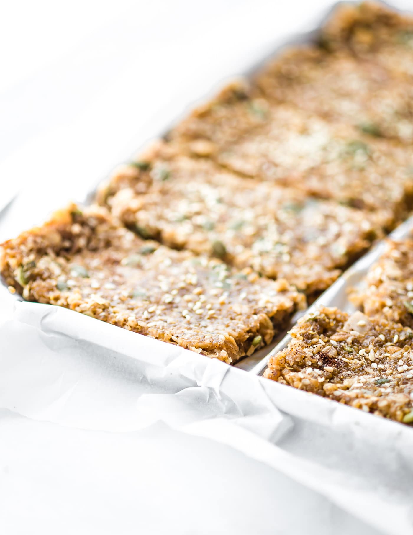 Maple sesame quinoa bars lined up on white parchment paper