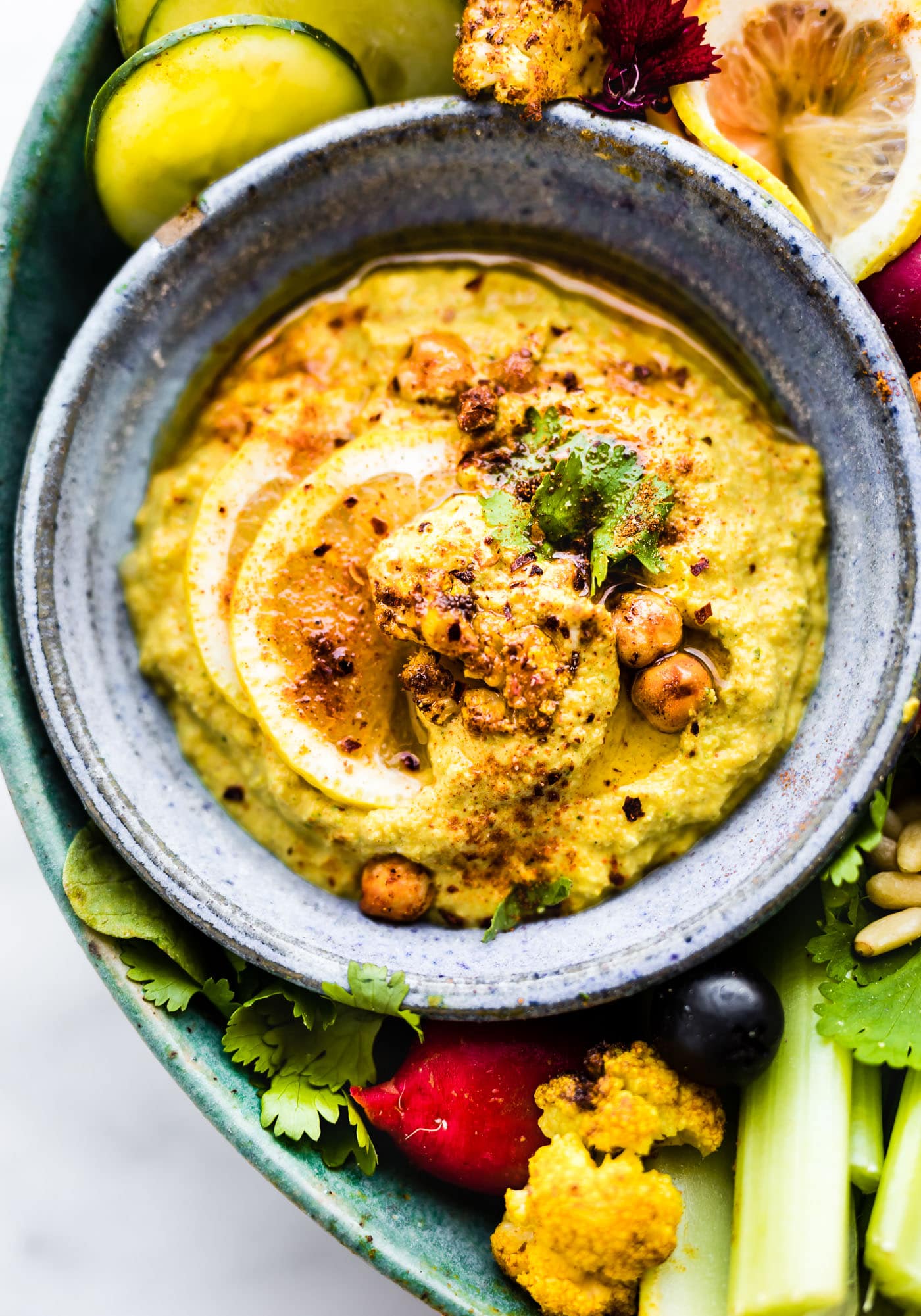 Tandoori Roasted Cauliflower dip in grey stone bowl topped with seasoning and chickpeas.