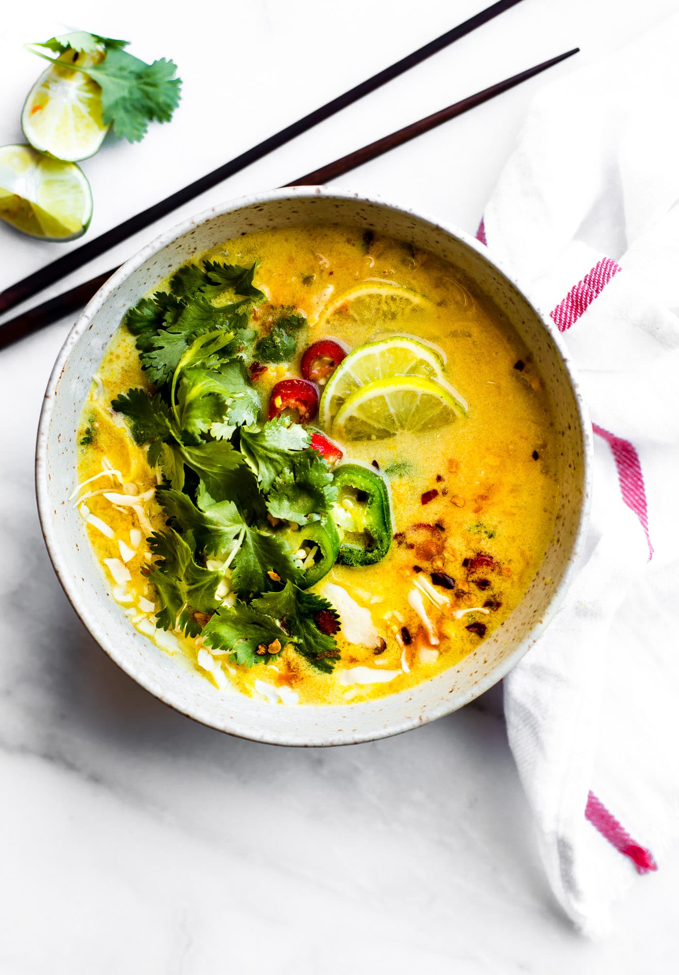 Overhead view Thai coconut cabbage soup in stone bowl topped with fresh cilantro and jalapeño slices.